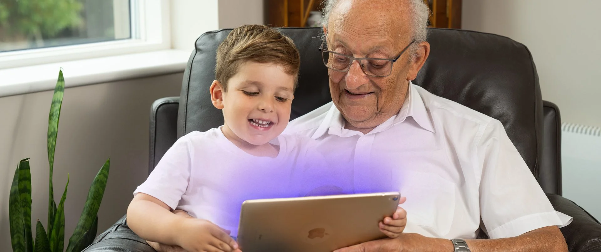 grandpa with grandson looking at jewish care website on an iPad