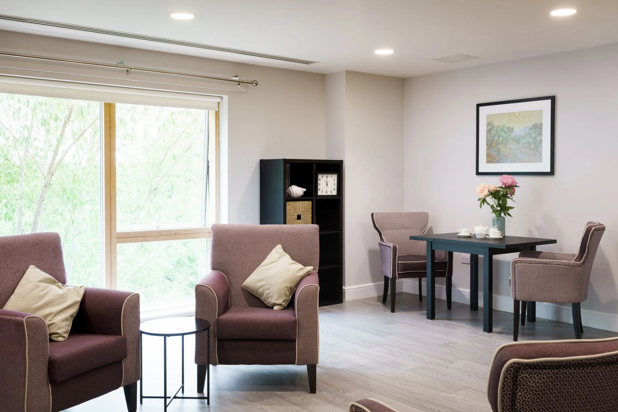 A calm, purple lounge space with arm chairs and a table with a tea service set up